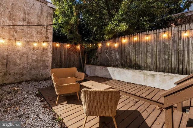 a view of a patio with couches table and chairs with wooden fence