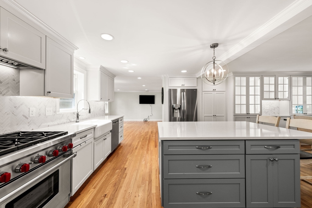 166 Hillcrest Road Needham, MA 02492 - Photo 9 of 36 a large kitchen with kitchen island a stove a sink dishwasher and white cabinets with wooden floor