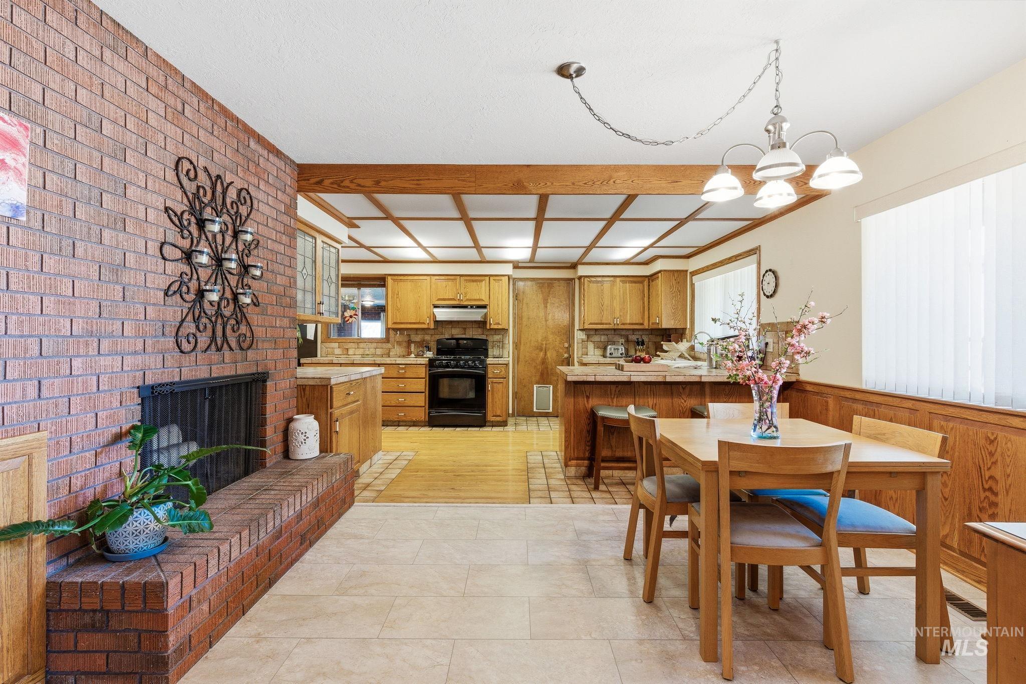 12055 West McMillan Road Boise, ID 83713 - Photo 12 of 42 Dining space featuring a brick fireplace, wood walls, suspended lighting, wainscoting, and brick wall