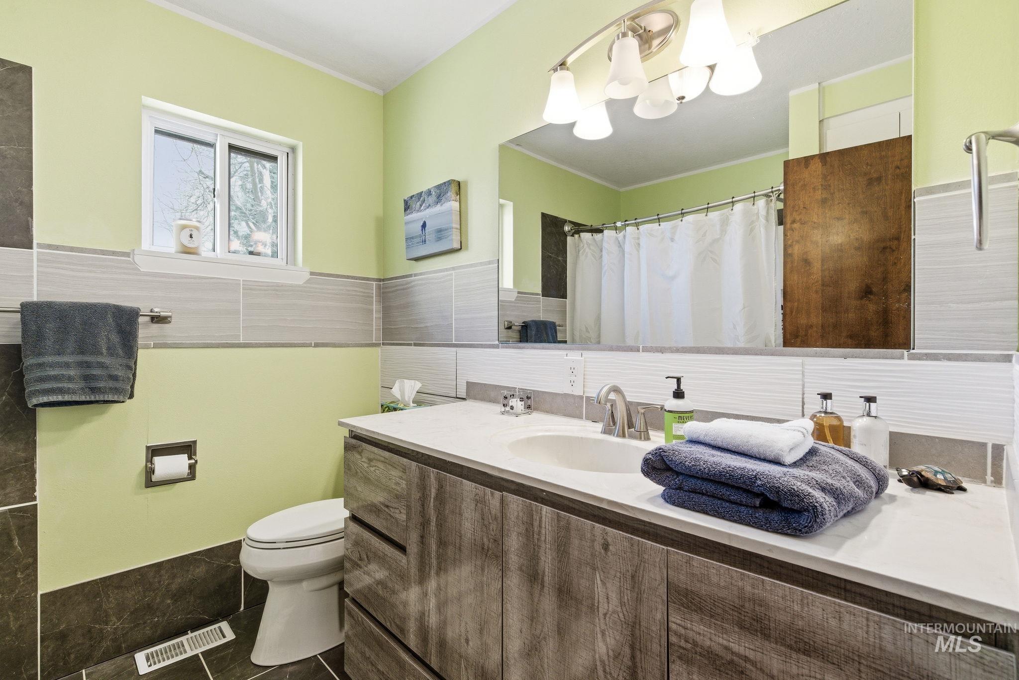12055 West McMillan Road Boise, ID 83713 - Photo 17 of 42 Full bath featuring vanity, a shower with shower curtain, tile walls, dark tile patterned flooring, and crown molding