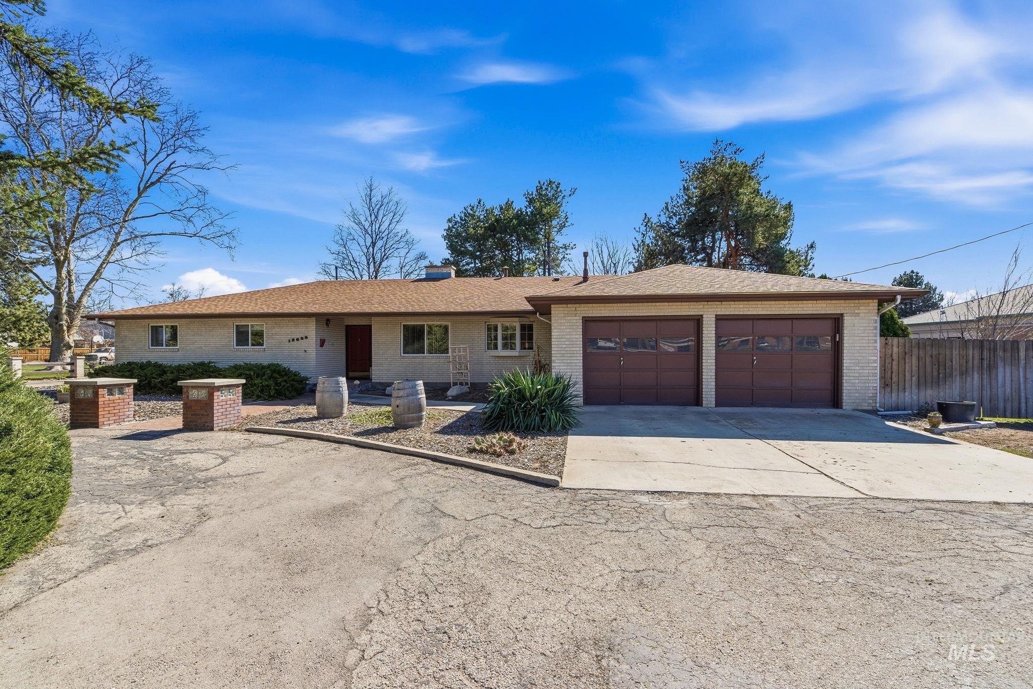 12055 West McMillan Road Boise, ID 83713 - Photo 2 of 42 Single story home with concrete driveway, brick siding, a garage, roof with shingles, and a chimney