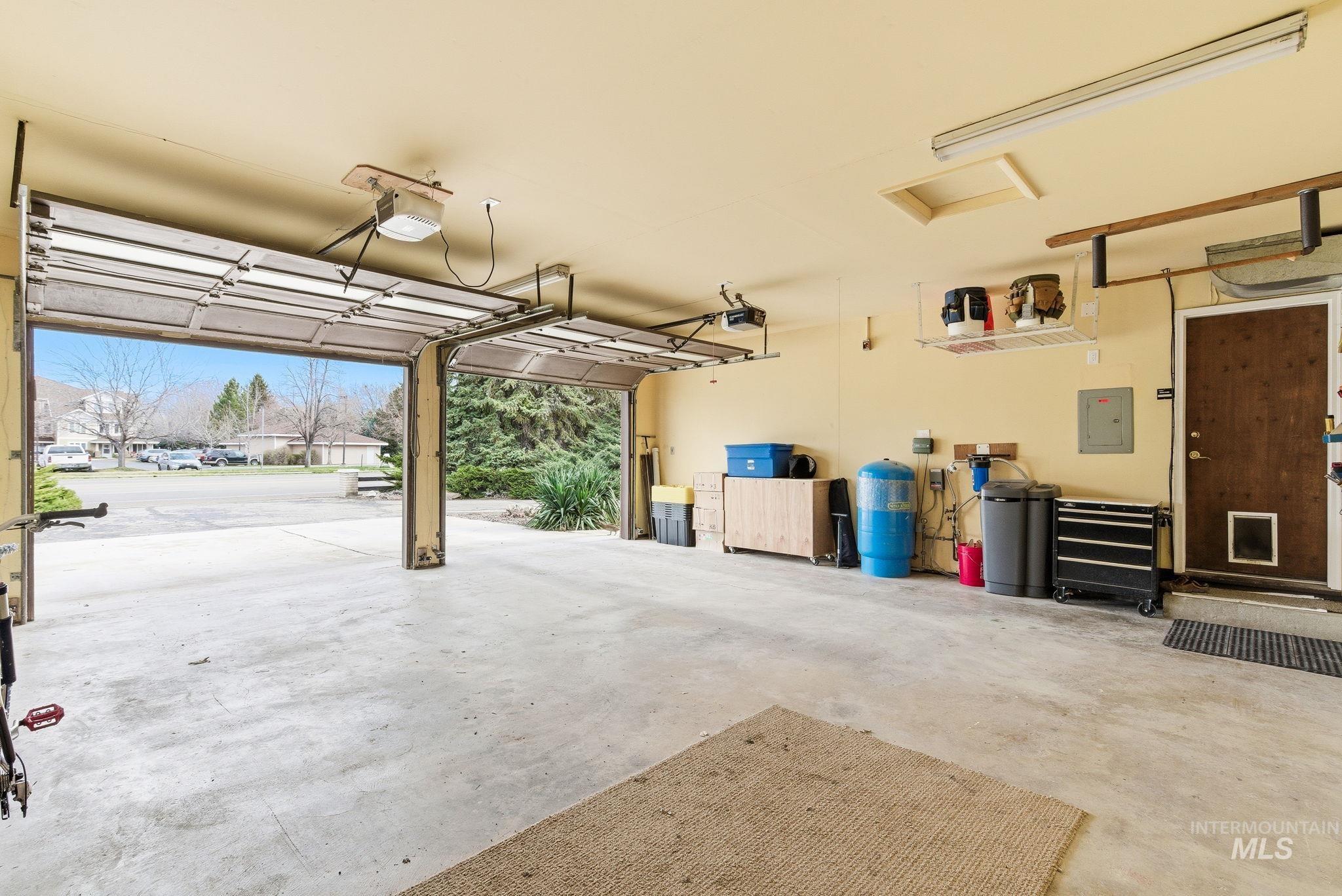 12055 West McMillan Road Boise, ID 83713 - Photo 21 of 42 Garage featuring electric panel, a garage door opener, and a residential view