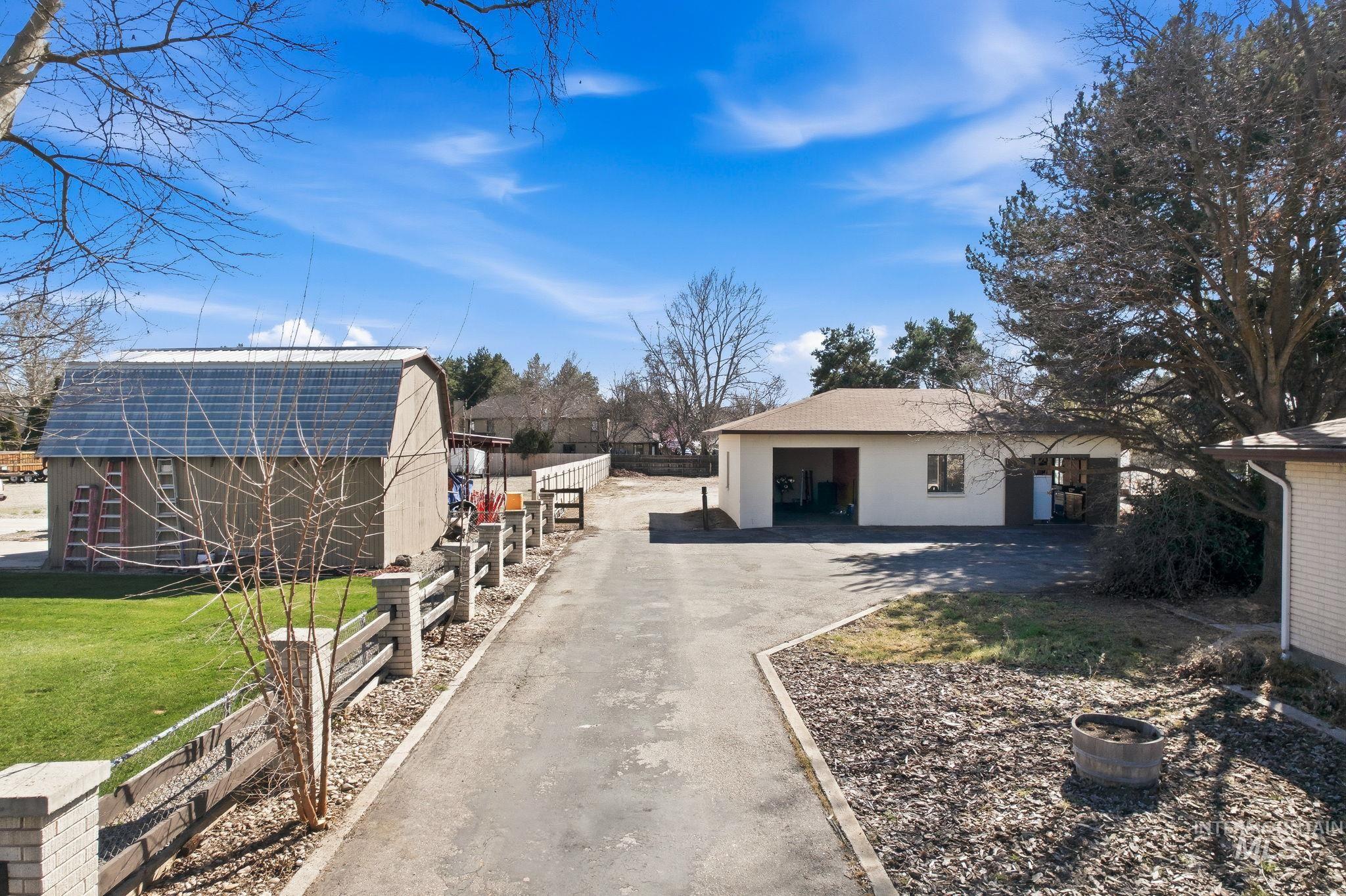 12055 West McMillan Road Boise, ID 83713 - Photo 28 of 42 View of property exterior featuring stucco siding, an outdoor structure, and driveway