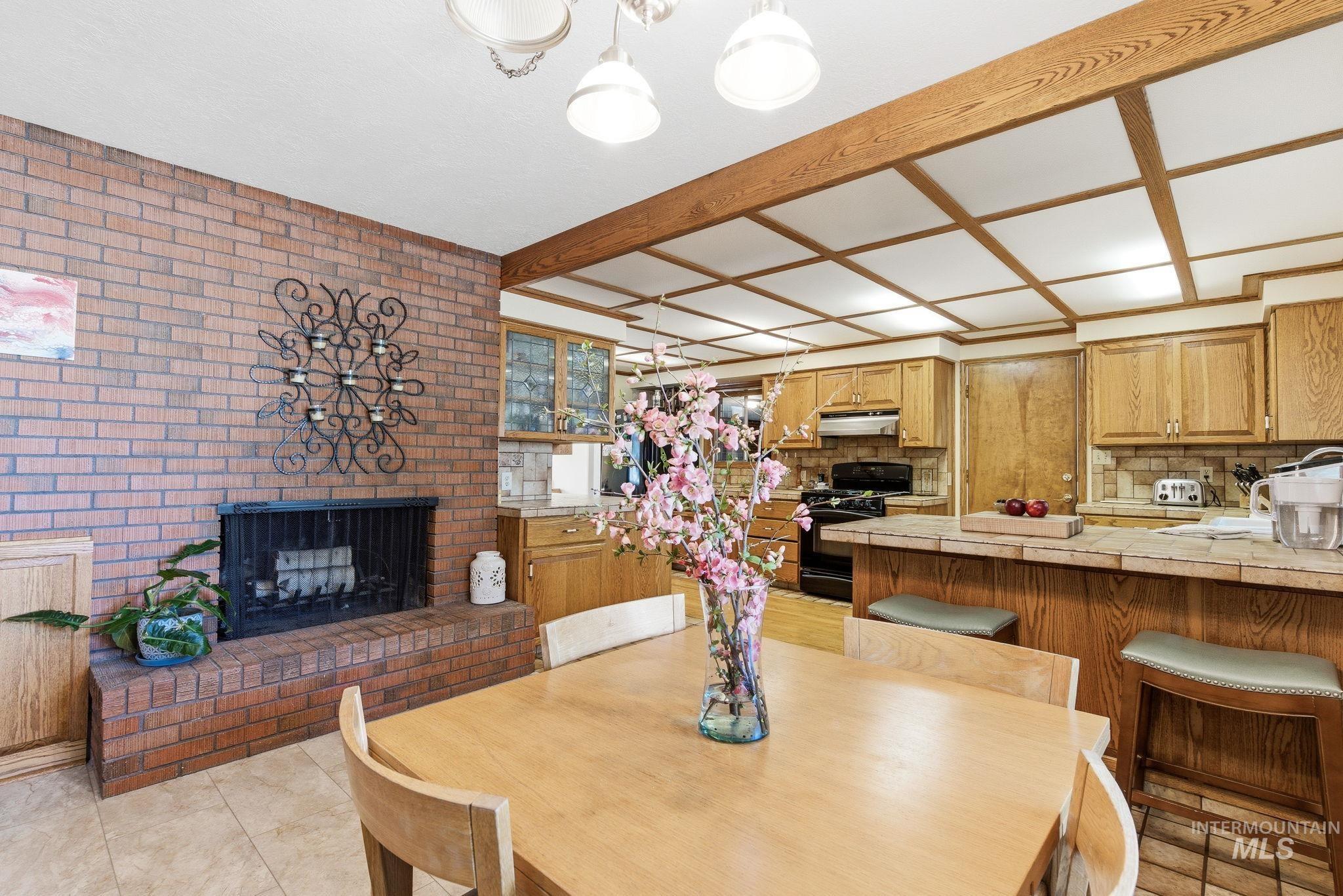 12055 West McMillan Road Boise, ID 83713 - Photo 10 of 42 Dining area featuring a brick fireplace and beamed ceiling