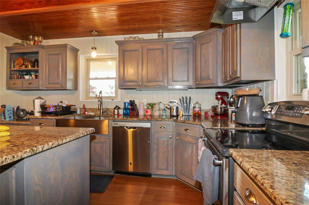 1001 Sandy Ridge Road Scurry, TX 75158 - Photo 18 of 35 Kitchen featuring wood-finish cabinetry, granite countertops, stainless steel appliances, a farmhouse-style sink, and a beadboard backsplash
