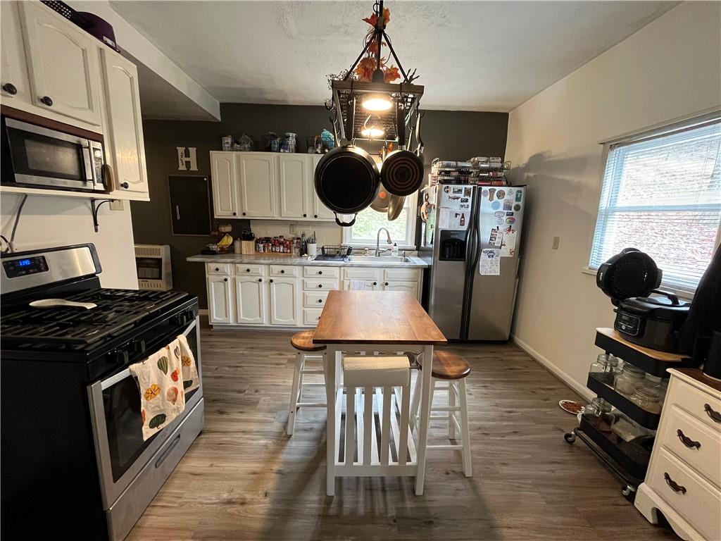 197 Oak Road Holbrook, PA 15341 - Photo 8 of 17 a kitchen with stainless steel appliances granite countertop a stove top oven a sink a dining table and chairs with wooden floor