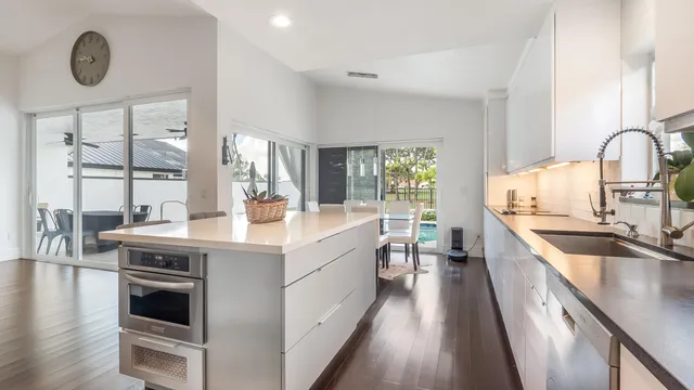 a kitchen with kitchen island granite countertop a stove a sink and white cabinets with wooden floor
