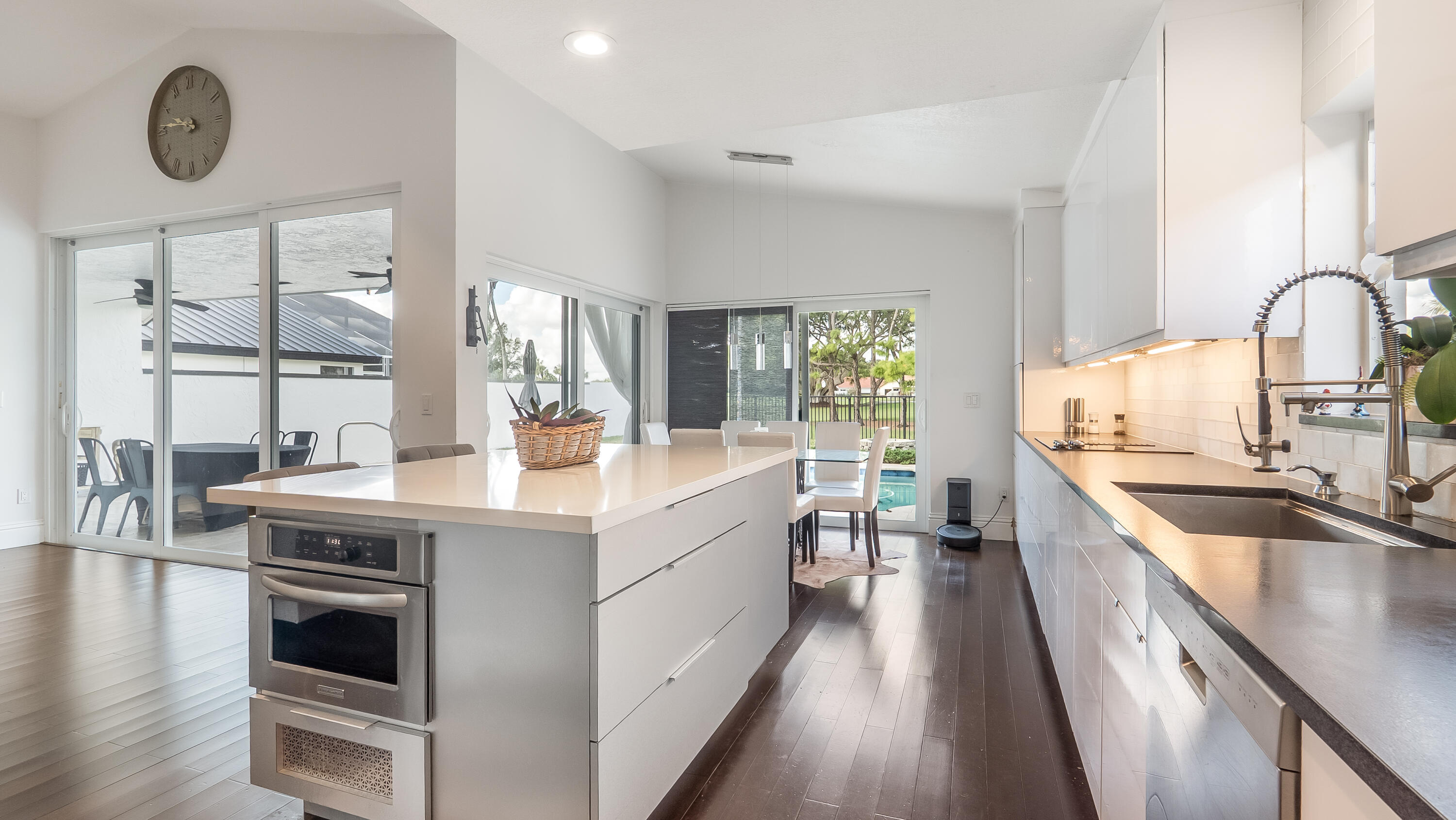 10208 Sunset Bend Drive Boca Raton, FL 33428 - Photo 3 of 40 a kitchen with kitchen island granite countertop a stove a sink and white cabinets with wooden floor