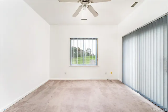 an empty room with wooden floor chandelier fan and windows