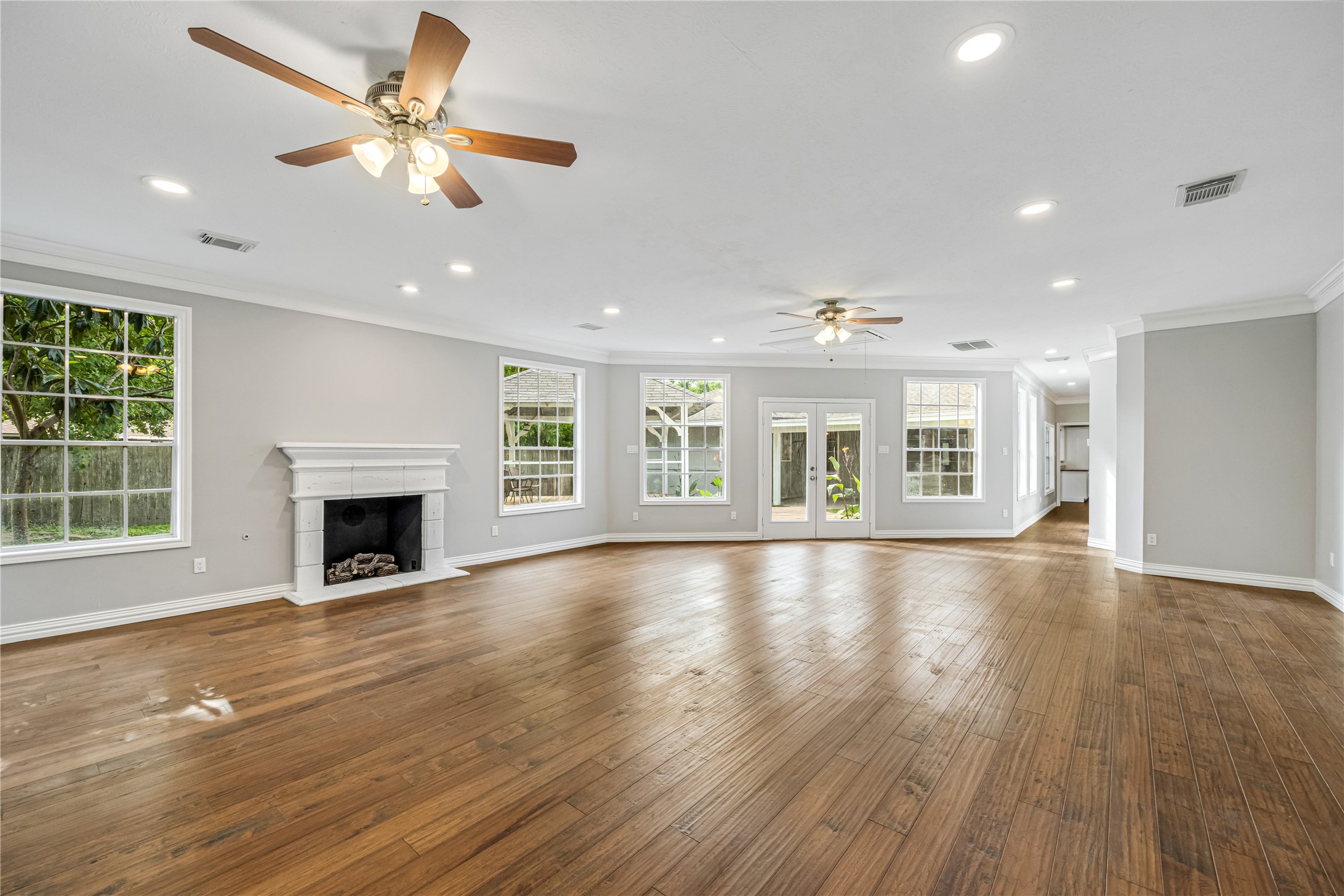 9806 Tanager Lane Conroe, TX 77385 - Photo 15 of 28 an empty room with windows fireplace and a kitchen view
