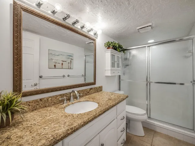 a bathroom with a granite countertop sink a toilet and shower