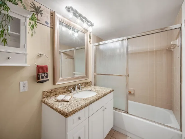 a bathroom with a granite countertop shower sink and mirror