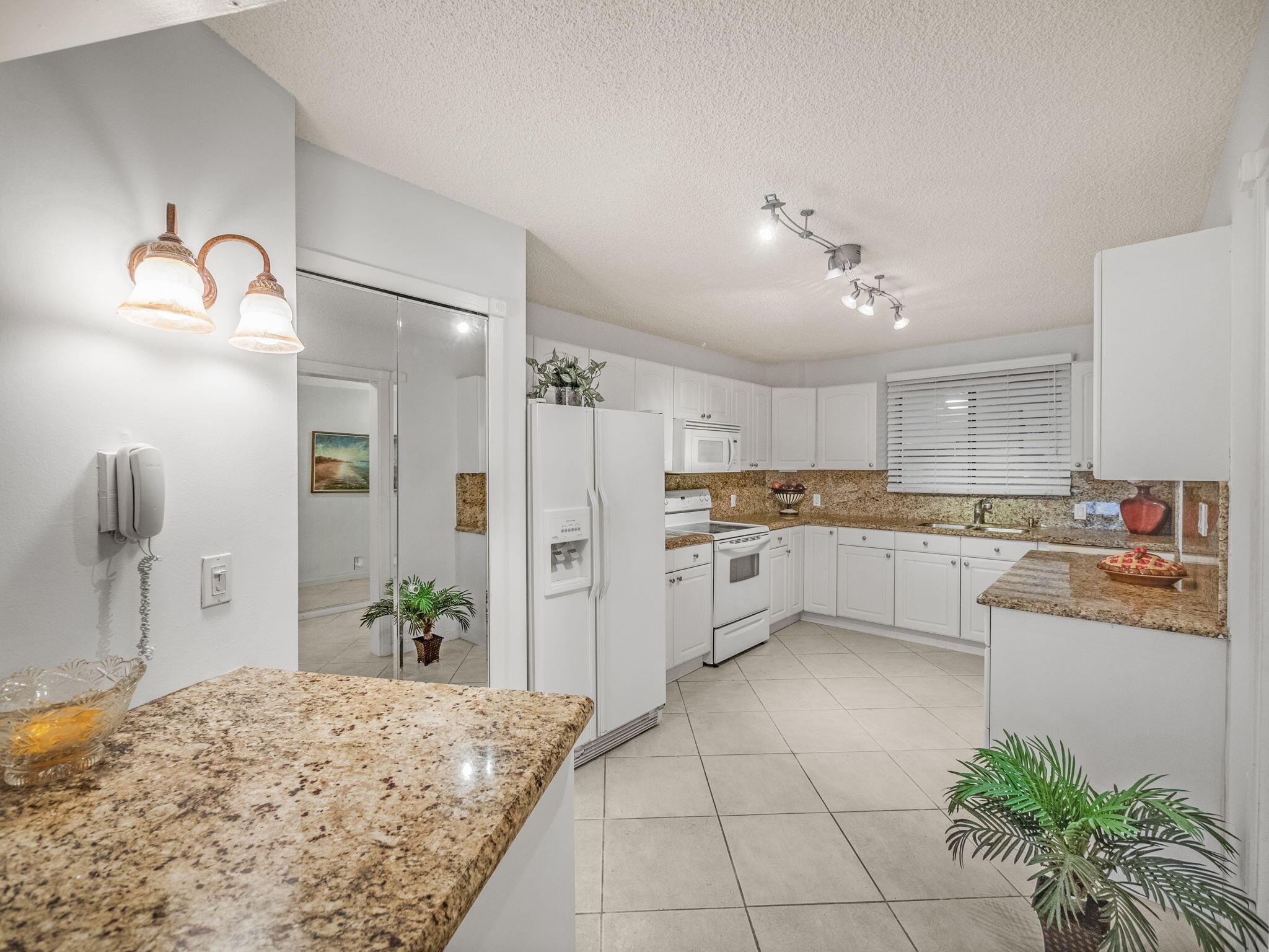 3525 South Ocean Boulevard, Unit 107 South Palm Beach, FL 33480 - Photo 9 of 21 a kitchen with white cabinets and white appliances