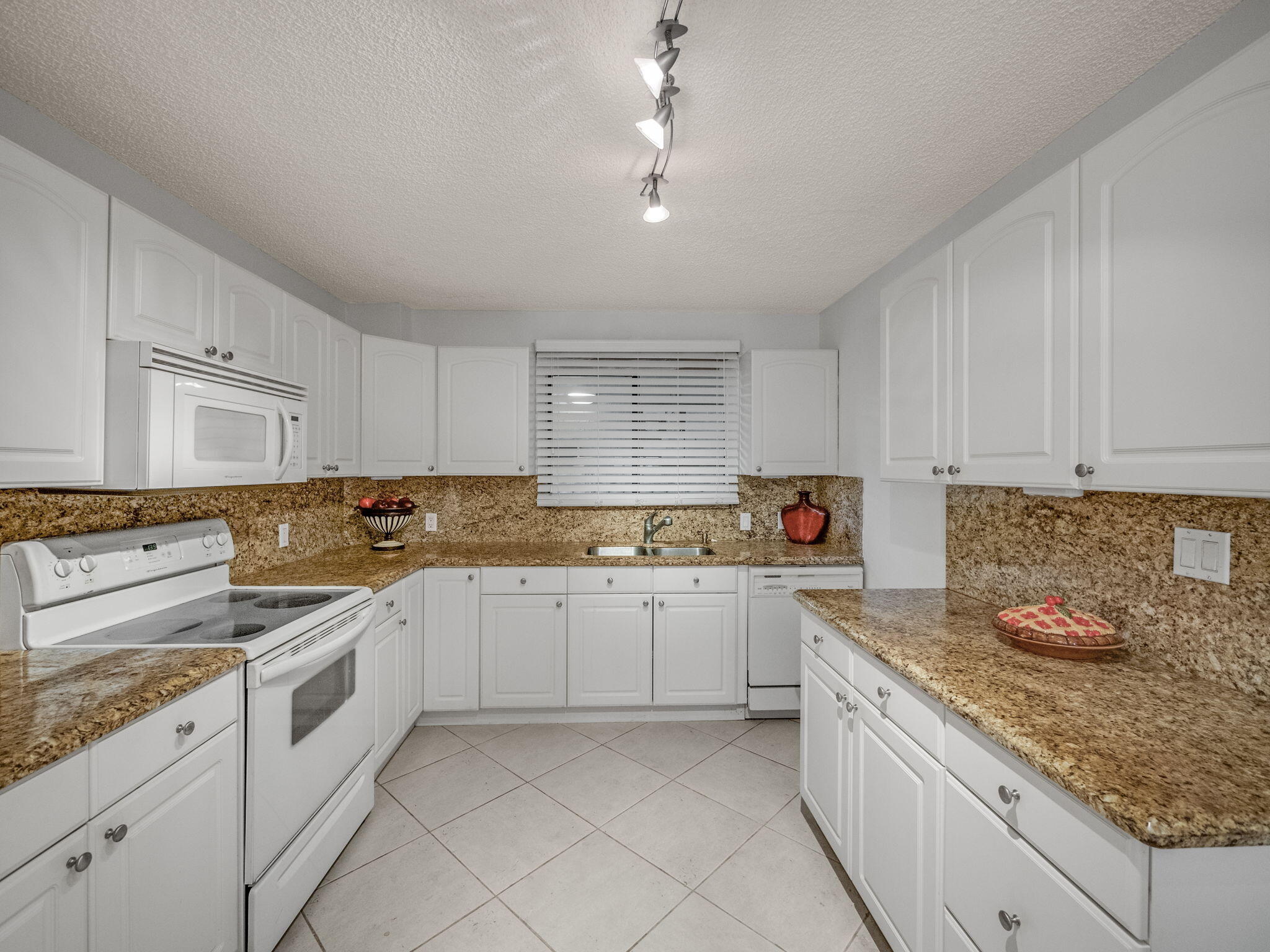 3525 South Ocean Boulevard, Unit 107 South Palm Beach, FL 33480 - Photo 10 of 21 a kitchen with granite countertop white cabinets and white appliances