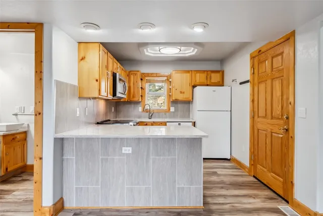 a kitchen with a refrigerator a stove a sink dishwasher and wooden cabinets with wooden floor