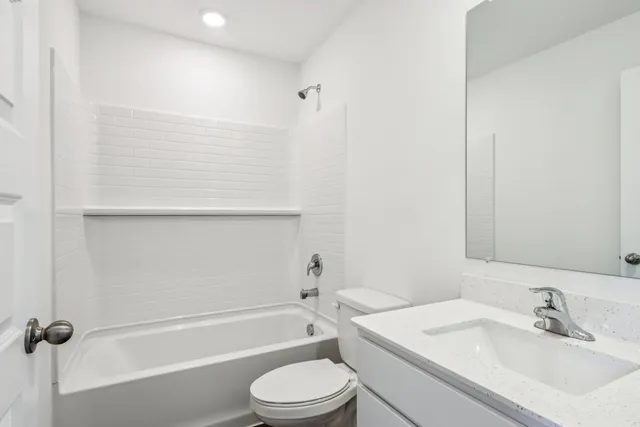 a bathroom with a bathtub shower sink vanity and toilet