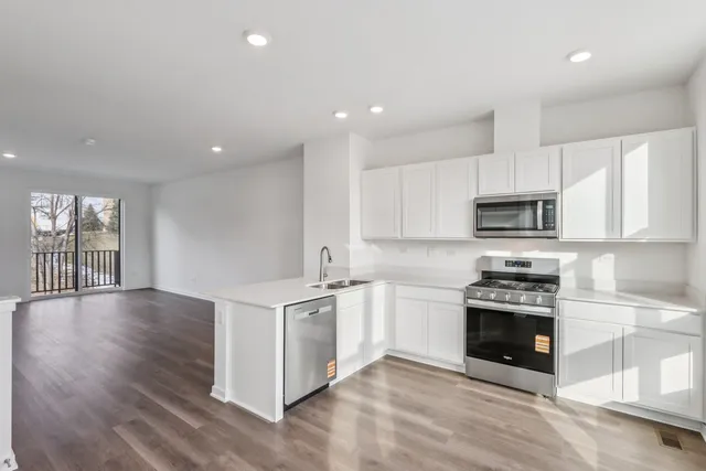 a kitchen with stainless steel appliances granite countertop a stove top oven a sink and a granite counter tops with white cabinets