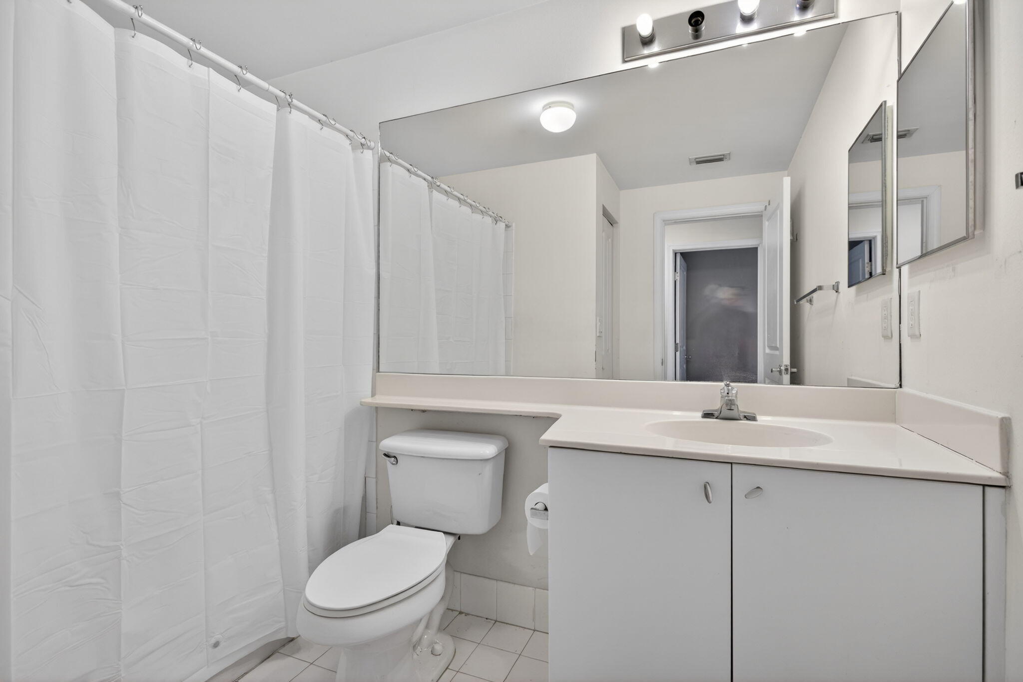 5880 West Sample Road, Unit 206 Coral Springs, FL 33067 - Photo 14 of 37 a bathroom with a toilet a sink and mirror