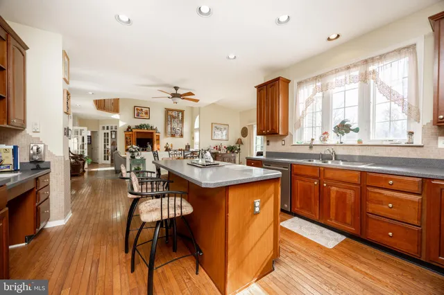 a open kitchen with stainless steel appliances granite countertop a stove top oven a sink dishwasher and cabinets with wooden floor