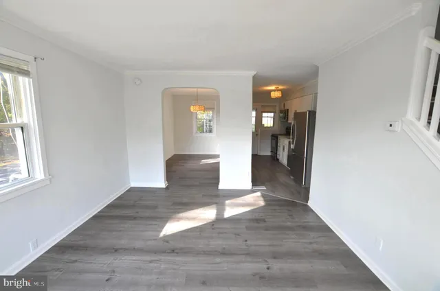 a view of a hallway with wooden floor and a living room