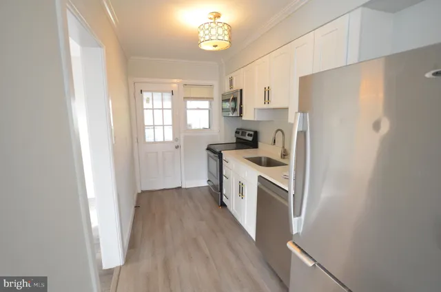 a kitchen with a refrigerator a sink a stove a refrigerator cabinets and wooden floor