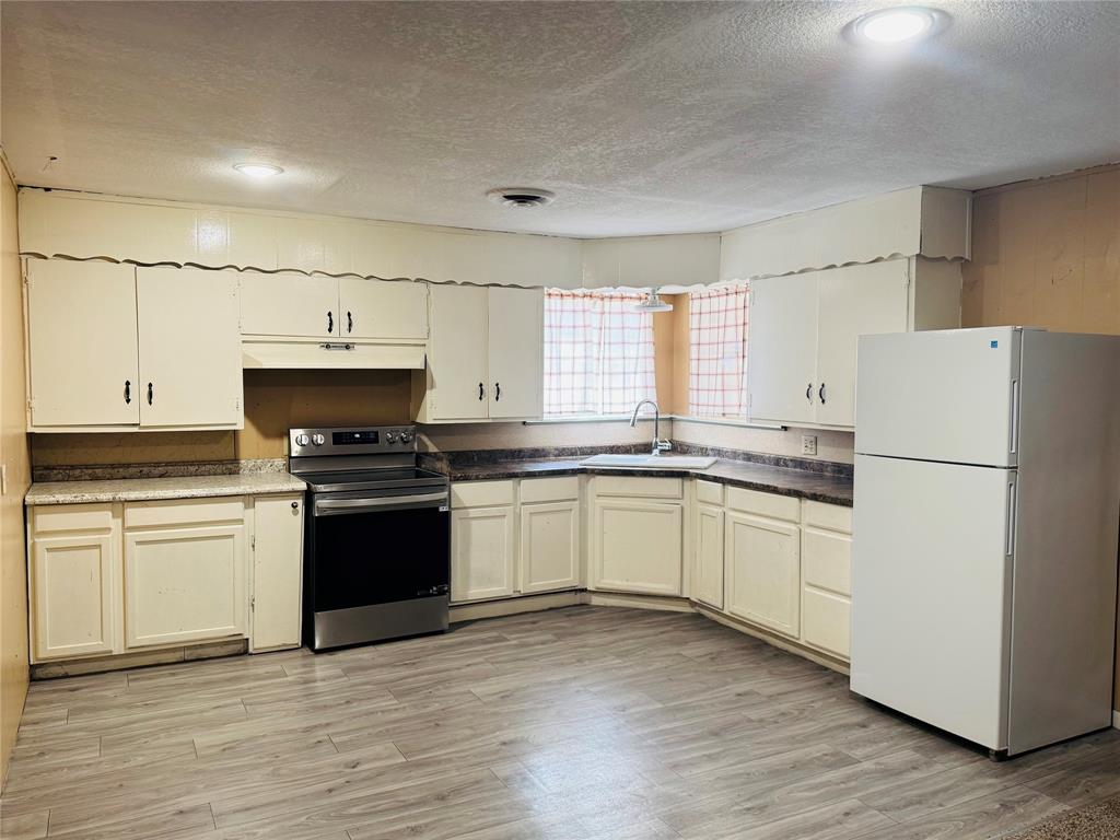 306 North Ave D Haskell, TX 79521 - Photo 2 of 7 a kitchen with granite countertop white cabinets and white appliances