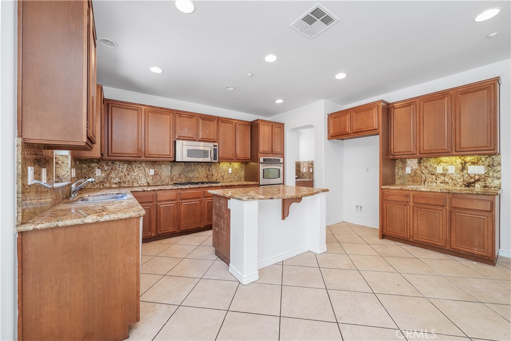 5662 Galasso Avenue Fontana, CA 92336 - Photo 12 of 34 a kitchen with stainless steel appliances granite countertop a stove top oven a sink a counter top space and cabinets