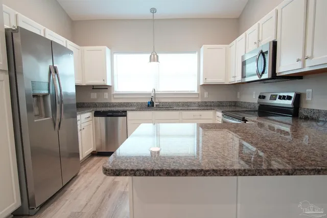 a kitchen with stainless steel appliances granite countertop a refrigerator a stove and a sink with granite countertops