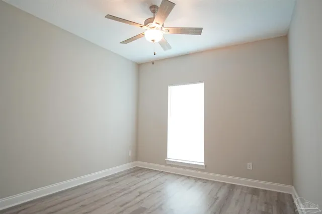 an empty room with a window and a fan
