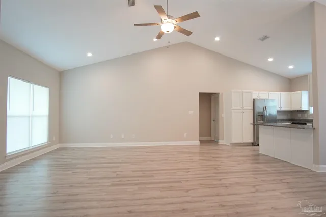 a view of an empty room with a window and kitchen view