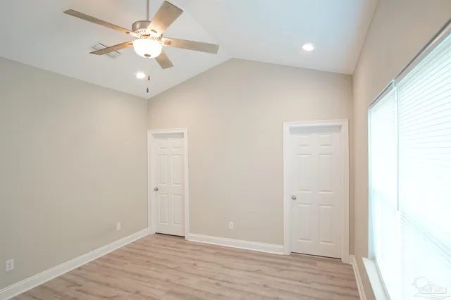 an empty room with wooden floor and ceiling fan