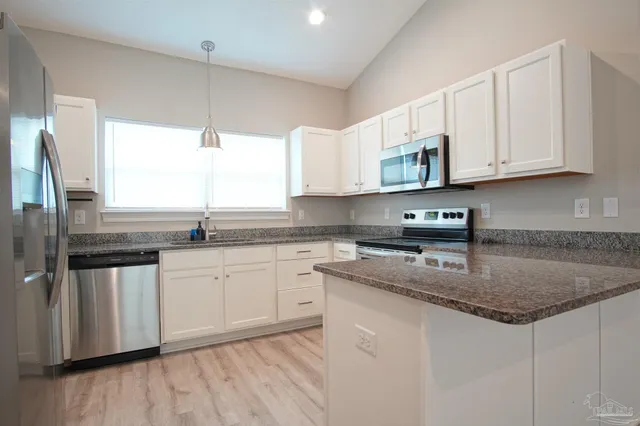 a kitchen with stainless steel appliances granite countertop a sink a stove a microwave a refrigerator and cabinets