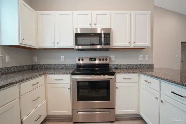 a kitchen with white cabinets and stainless steel appliances