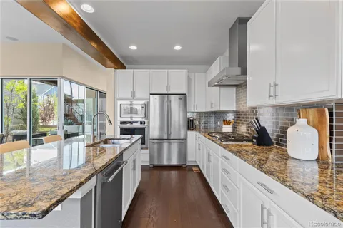 a large kitchen with granite countertop a large counter top appliances and cabinets