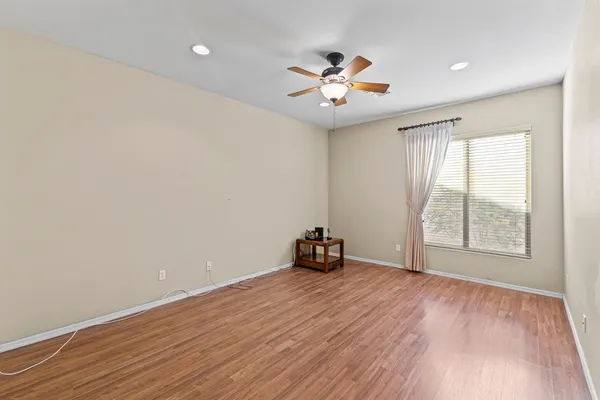 an empty room with wooden floor fan and windows