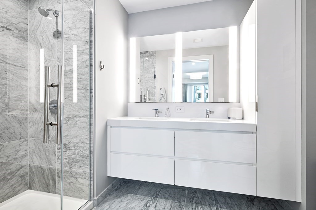 133 Seaport Boulevard, Unit 823 Boston, MA 02210 - Photo 10 of 30 a bathroom with a double vanity sink mirror and shower