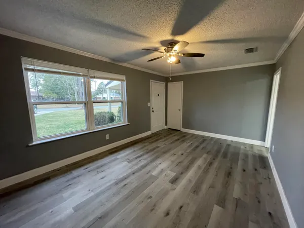 a view of an empty room with a window and wooden floor