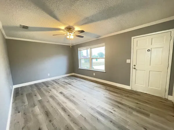 an empty room with wooden floor ceiling fan and windows