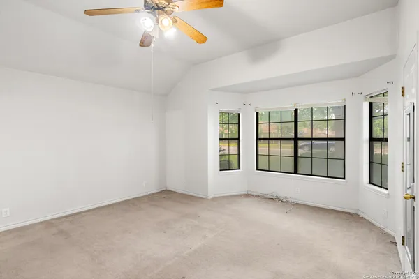 an empty room with windows and chandelier fan