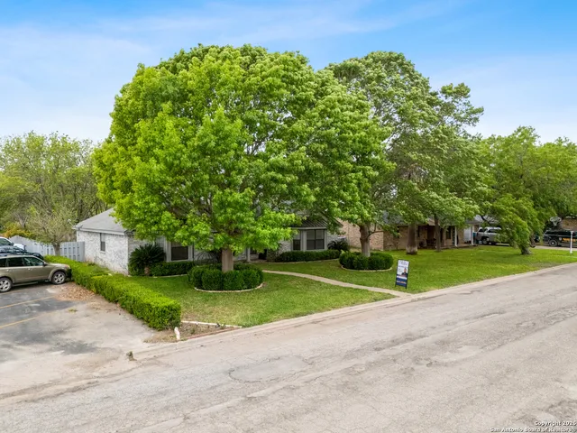 a view of a house with a big yard and large trees