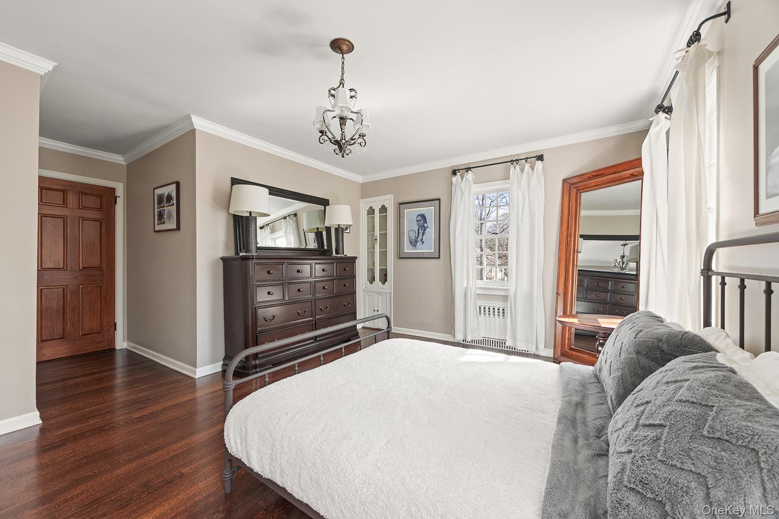 147 Valley Stream Road East Larchmont, NY 10538 - Photo 20 of 37 a bedroom with a large bed a chandelier and dresser