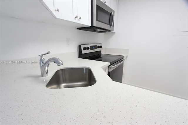a kitchen with white cabinets and black appliances
