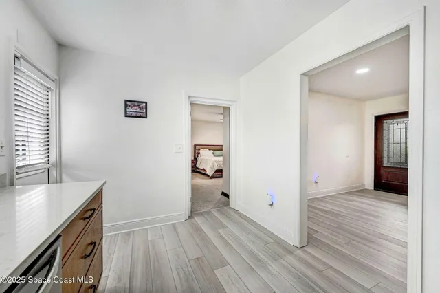 a view of a hallway with wooden floor and a bathroom