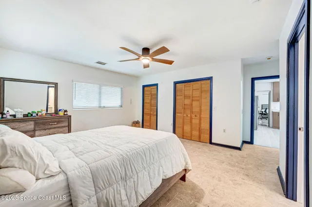 a spacious bedroom with a large bed a chandelier and windows