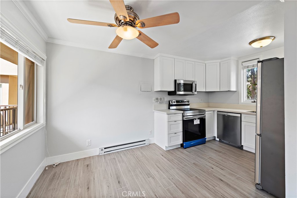 2037 South Coast Highway, Unit 11 Laguna Beach, CA 92651 - Photo 11 of 32 a kitchen with granite countertop a refrigerator cabinets and wooden floor