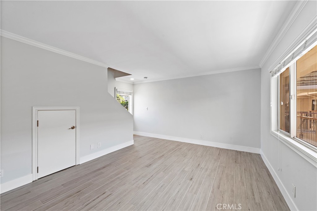 2037 South Coast Highway, Unit 11 Laguna Beach, CA 92651 - Photo 12 of 32 an empty room with wooden floor and windows