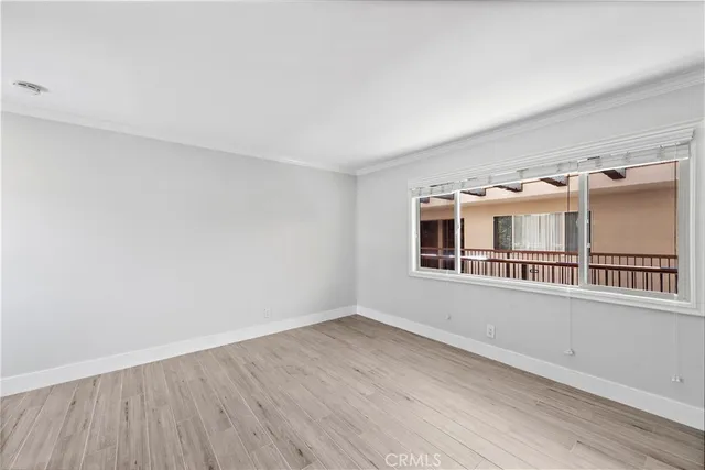 a view of an empty room with a window and wooden floor