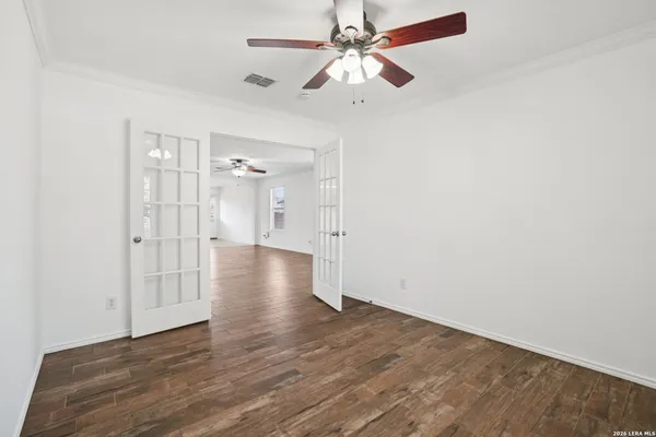 an empty room with wooden floor and fan