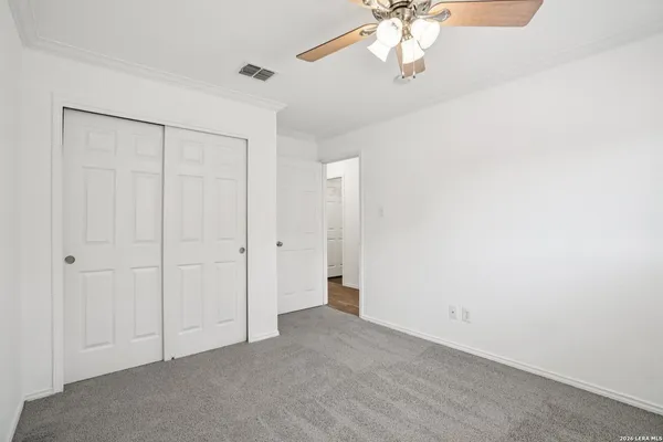 an empty room with a chandelier fan and closet