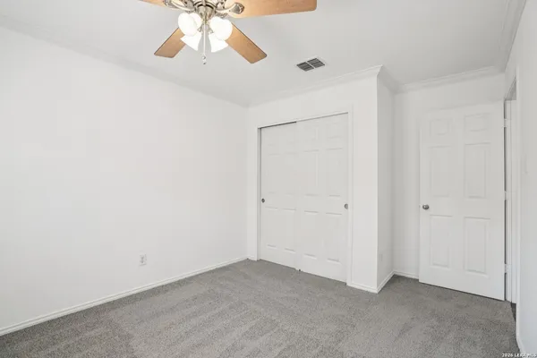 a view of an empty room and chandelier fan
